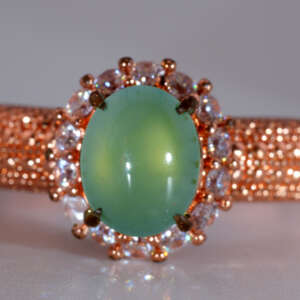 Front view of icy green Burmese jadeite cabochon ring with rose-gold pavé halo and bright white accent stones, size 8