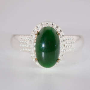 “Front-facing close-up of a natural green jadeite jade cabochon ring set in a silver mount with micro-pavé detailing