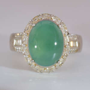 Front facing image of the jadeite ring featuring a large oval cabochon framed by brilliant accent stones