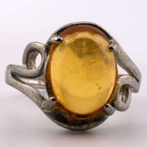 Adjustable silver ring featuring a polished bright-yellow Burmese amber cabochon, photographed close-up against a neutral background